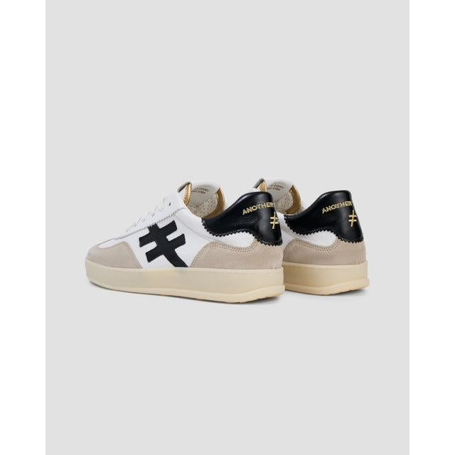 Buffalo Ladies White Leather Lace-Up Trainers with black and beige accents, featuring bold cross logo and trendy design.