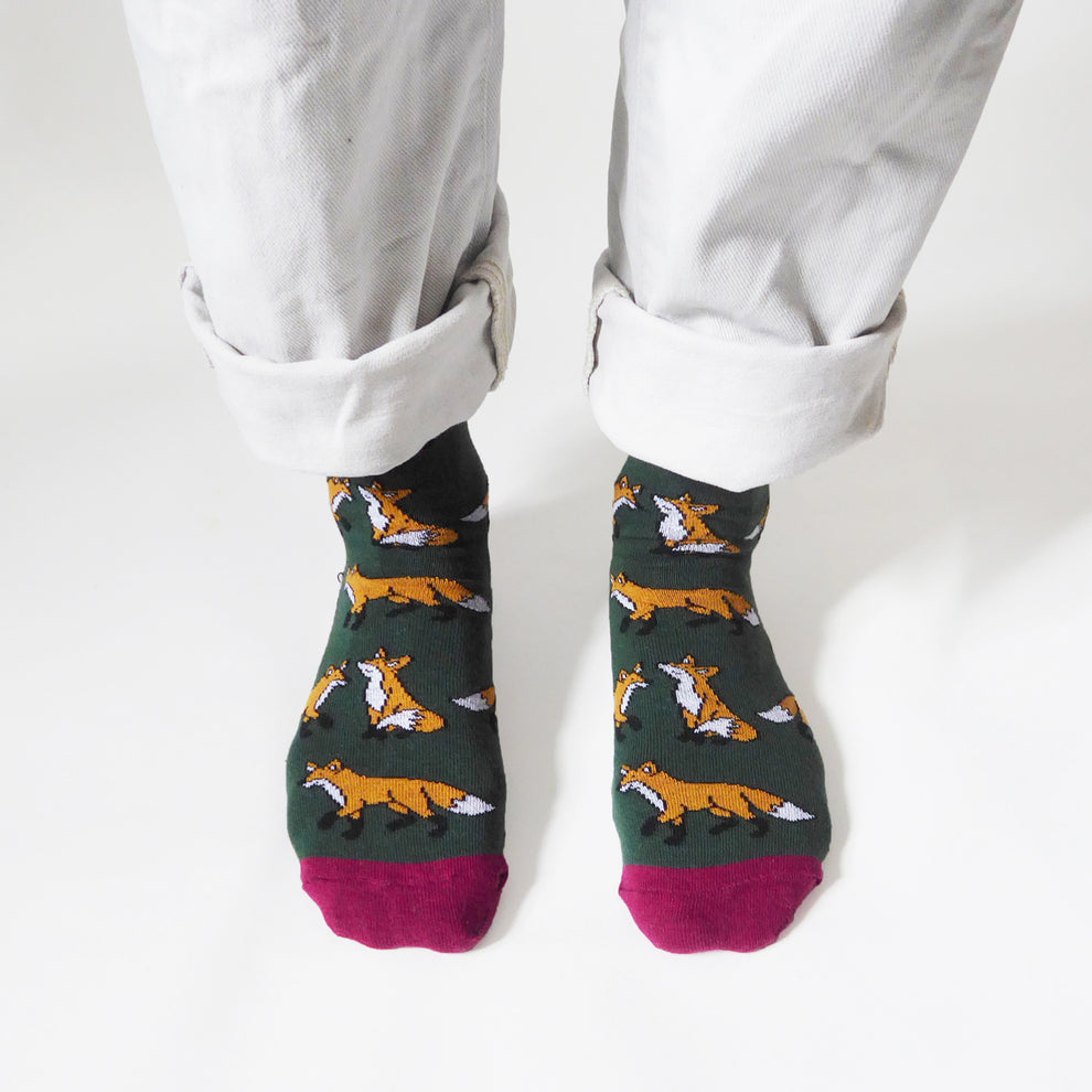 Barekind Save The Foxes bamboo socks with fox pattern, green and pink accents, worn with rolled white pants.