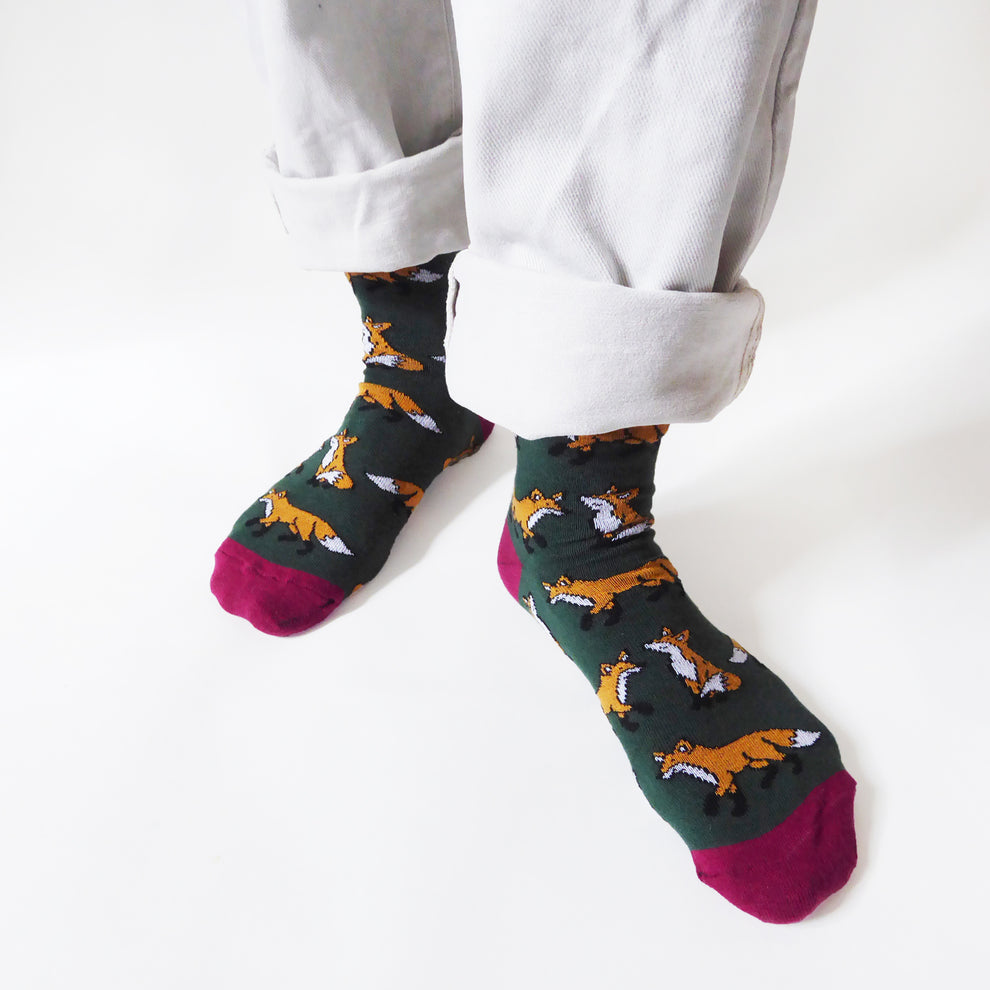 Barekind Save The Foxes bamboo socks with fox print, dark green, pink toes, worn with rolled white pants.