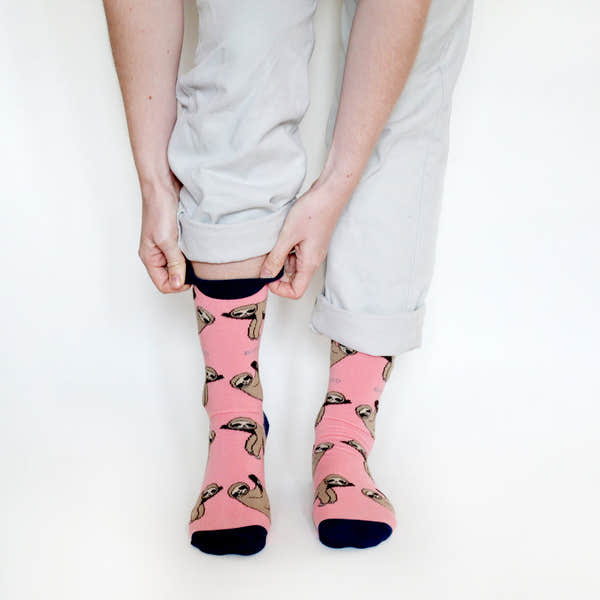 Barekind Save The Sloths pink socks with sloth pattern, navy toe and heel, worn with rolled light-colored pants.