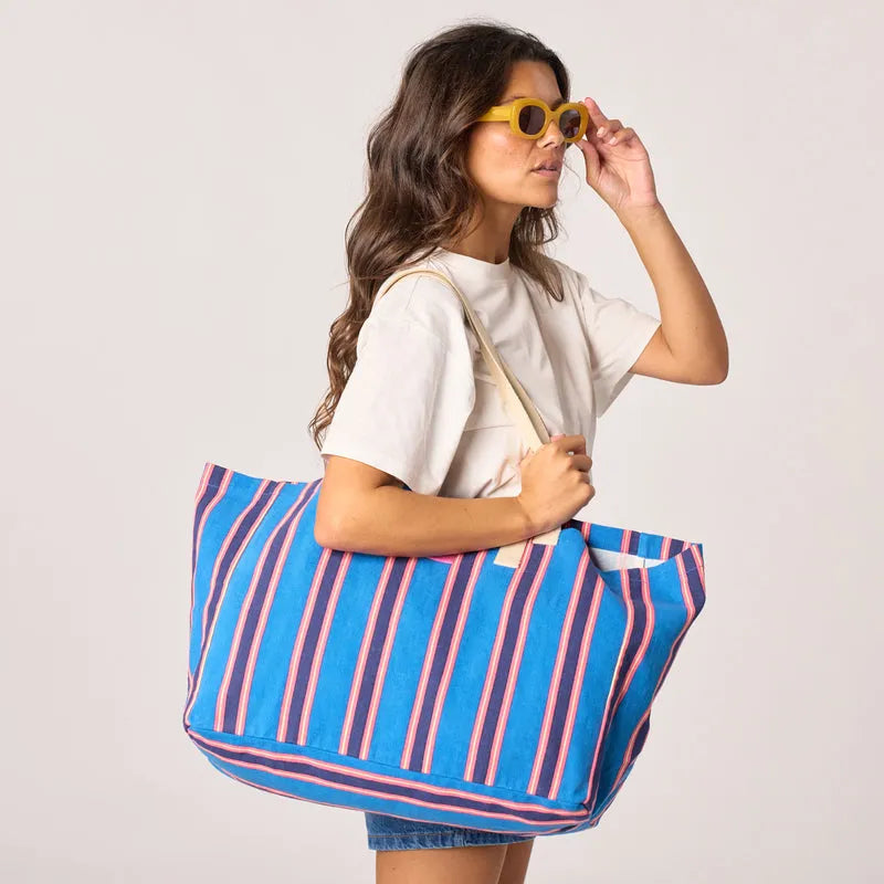 Woman carrying a blue striped Billy Belts 100% organic cotton shopping bag with beige handles, fashion accessory, eco-friendly tote.