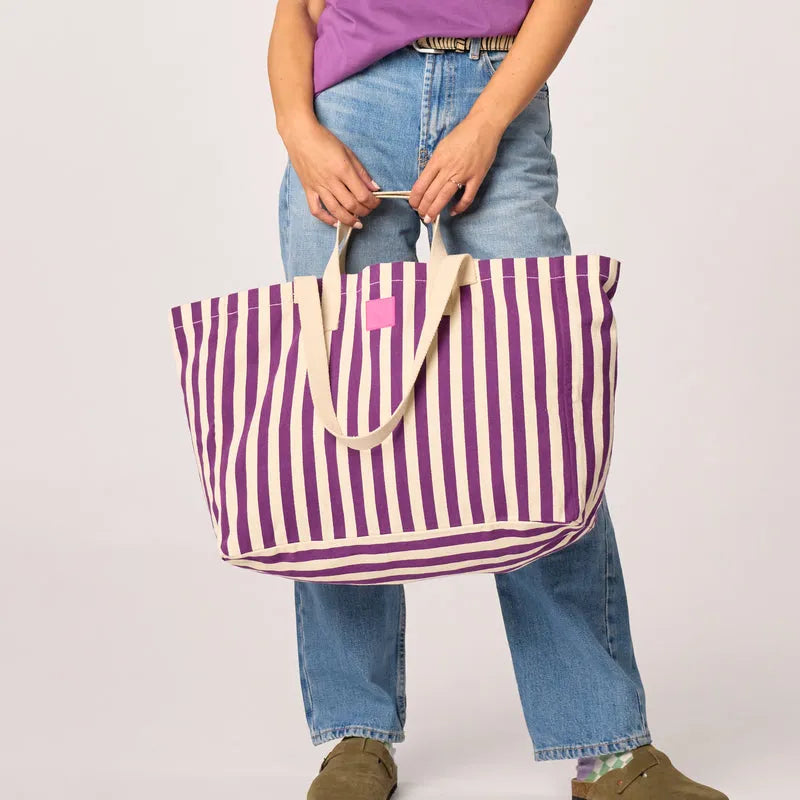 Billy Belts organic cotton shopping bag with purple and ecru vertical stripes, large size, casual style, held by a person in jeans.