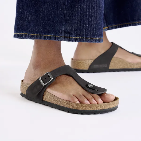 Women's black nubuck Birkenstock Gizeh arch support buckle sandals with cork footbed and rubber sole.