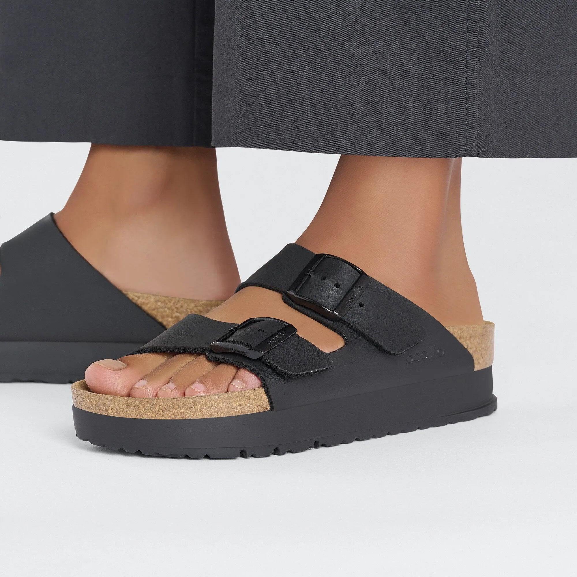 Black Birkenstock Papillio Arizona Flex Birkoflor platform sandals with narrow straps, buckle closures, and cork footbed.