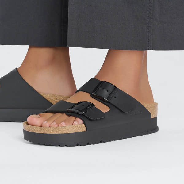 Black Birkenstock Papillio Arizona Flex Birkoflor platform sandals with narrow straps, buckle closures, and cork footbed.