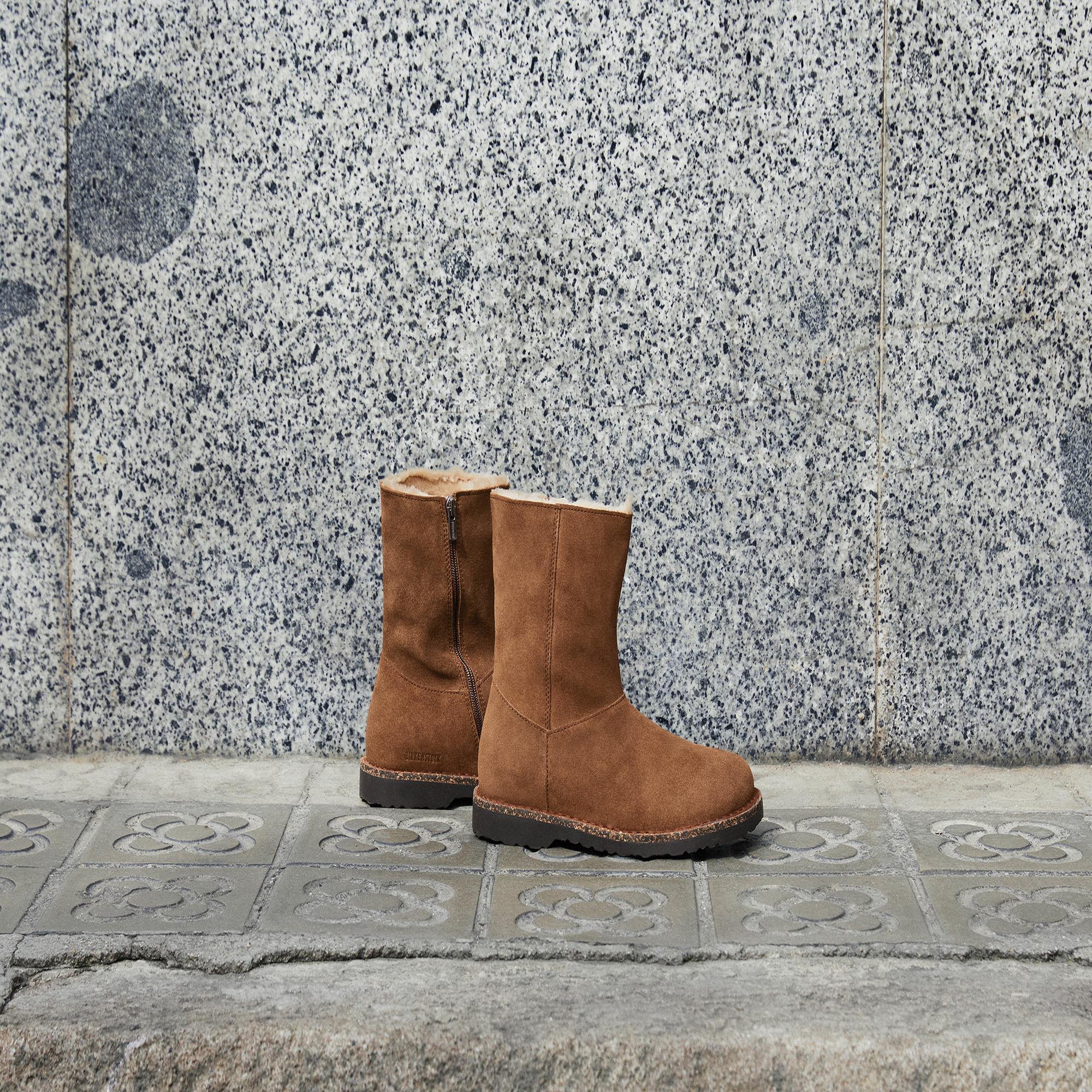 Birkenstock Uppsala Shearling Ladies Dark Tea Suede ankle boots with side zipper and arch support, placed on tiled sidewalk.
