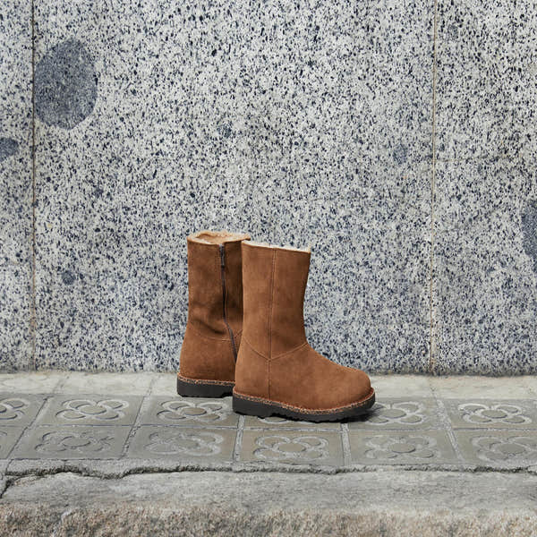 Birkenstock Uppsala Shearling Ladies Dark Tea Suede ankle boots with side zipper and arch support, placed on tiled sidewalk.