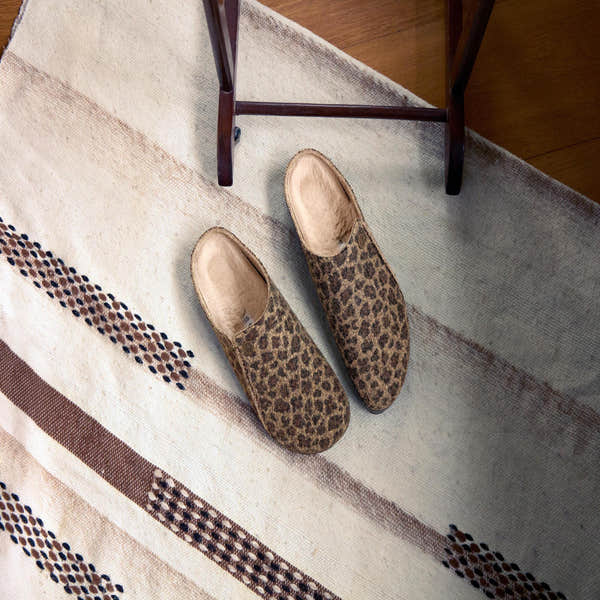 Birkenstock Zermatt Leopard shearling slip-on mules with textile arch support and faux fur lining, on beige patterned rug.