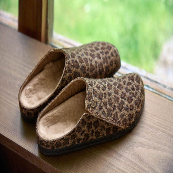 Birkenstock Zermatt Leopard Shearling slippers with textile exterior and arch support, lined with soft shearling, on wooden surface.