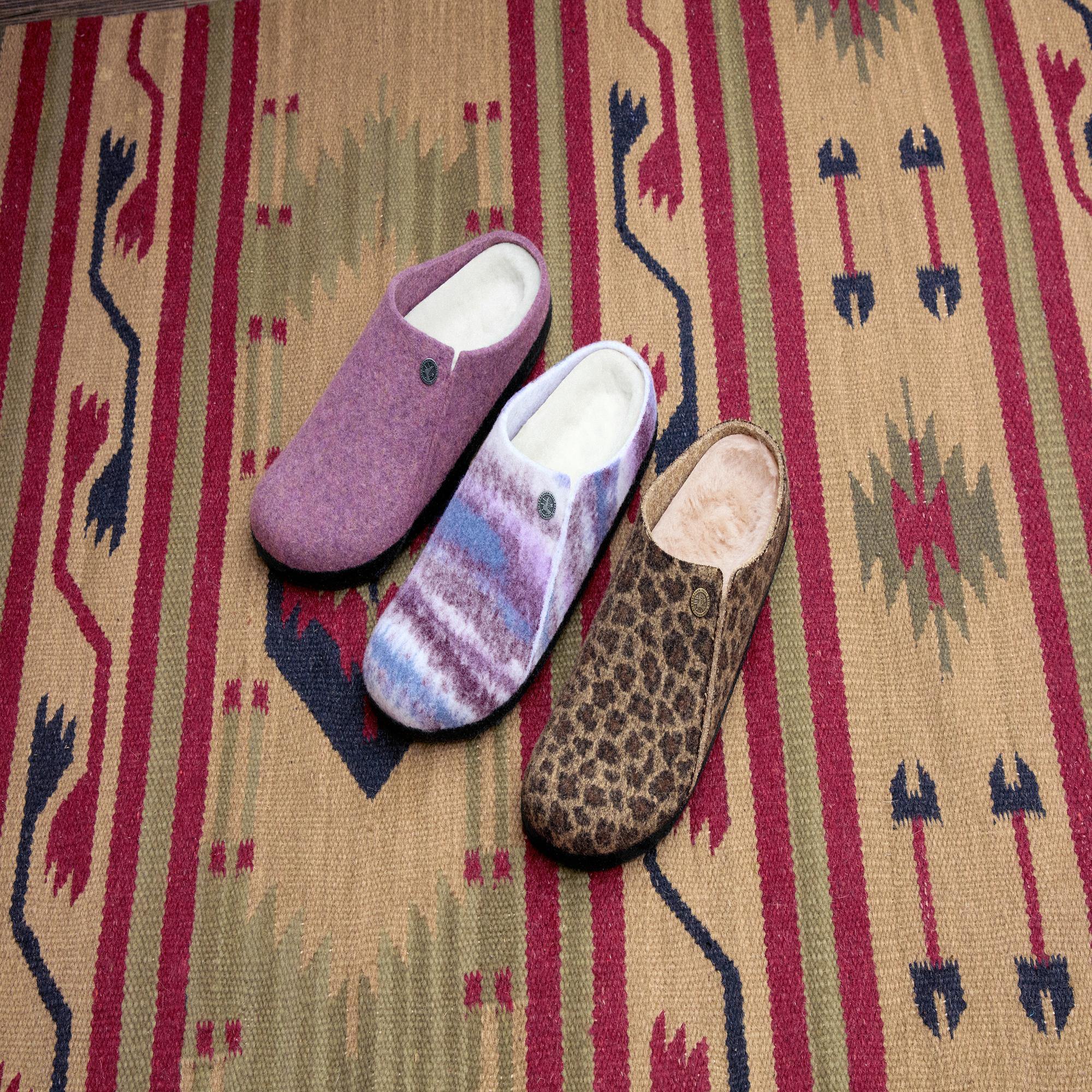 Birkenstock Zermatt Leopard Shearling slip-on mule slippers with arch support and leopard, pastel, and pink prints on a patterned rug.