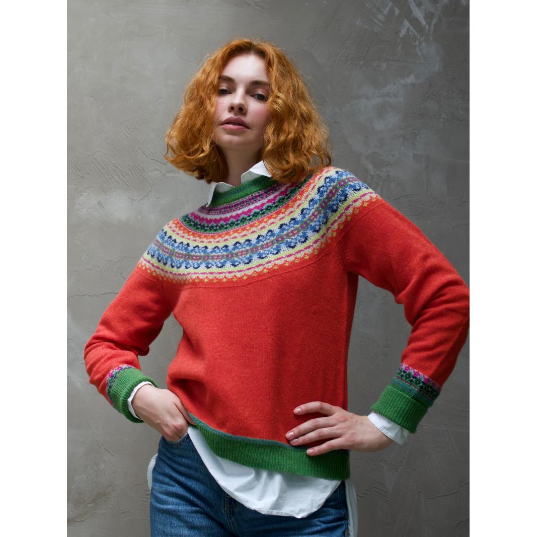 Eribe Alpine Short Sweater Bellarose with colorful Fair Isle yoke, red body, green cuffs and hem, layered over a white shirt, jeans.