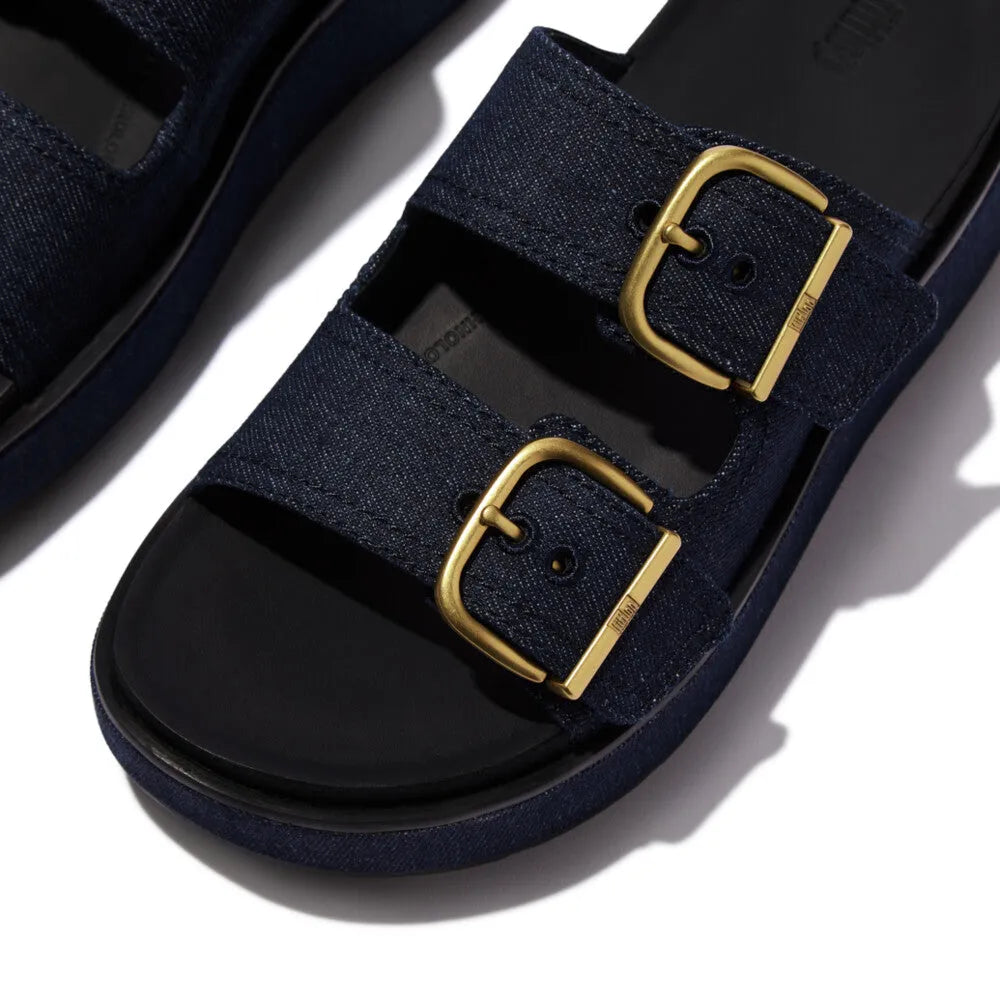 FitFlop ladies' dark denim textile slip-on sandals with double gold buckle straps.