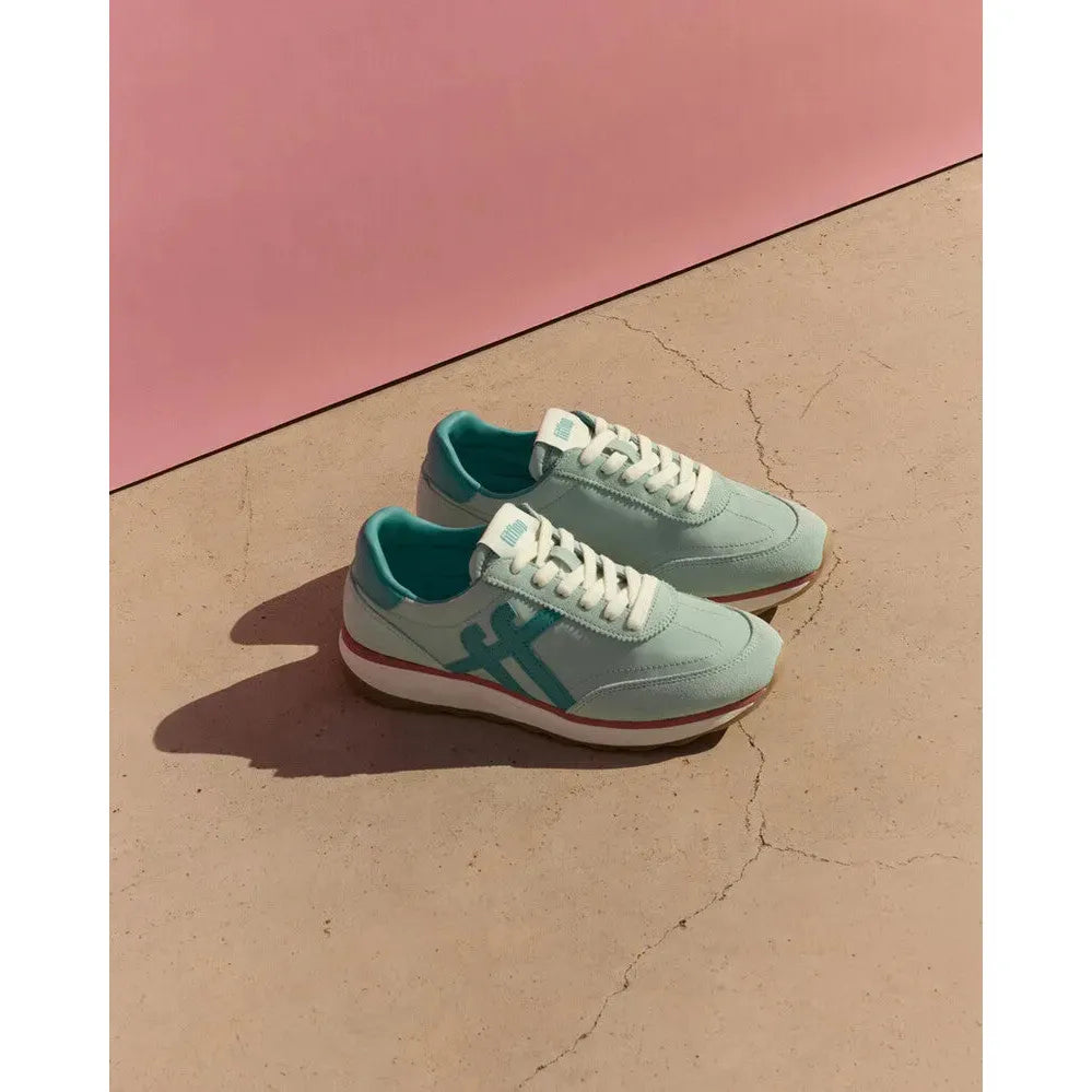 FitFlop Retro-Q FF ladies mint/teal leather and textile lace-up trainers on beige surface with pink background.