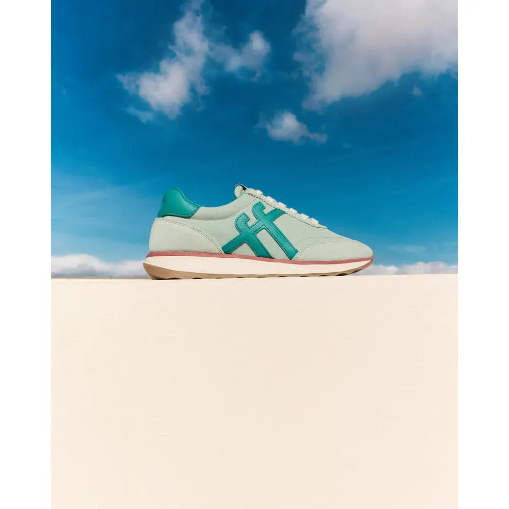 FitFlop Retro-Q FF ladies mint and teal leather and textile lace-up trainers on neutral surface with blue sky background.