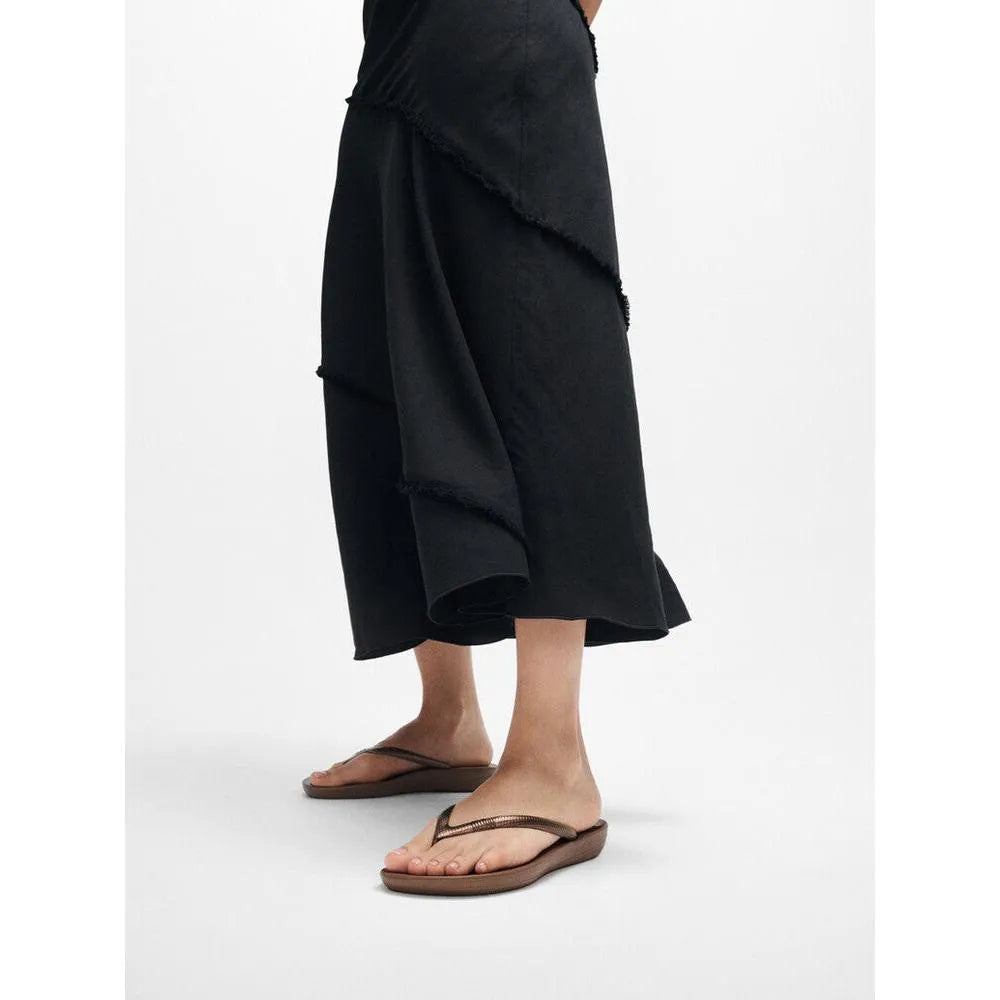 FitFlop E54-012 Iquishion Ladies Bronze T-bar Sandals with adjustable strap and cushioned sole, worn by a person in black clothing.