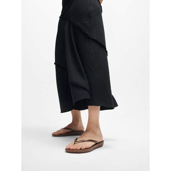FitFlop E54-012 Iquishion Ladies Bronze T-bar Sandals with adjustable strap and cushioned sole, worn by a person in black clothing.