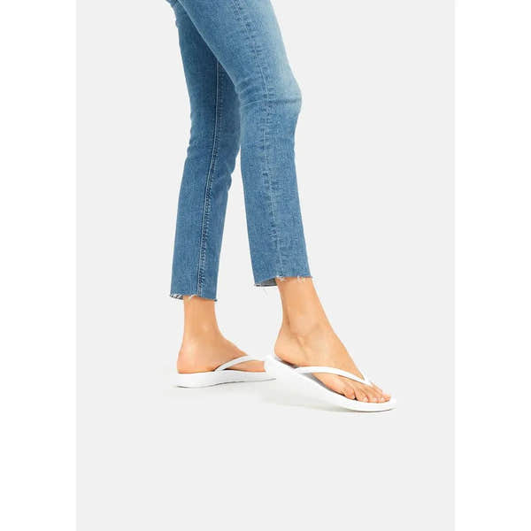 FitFlop E54-194 Iquishion women's white urban T-strap sandals, casual flip-flops with comfortable sole, worn with blue jeans.