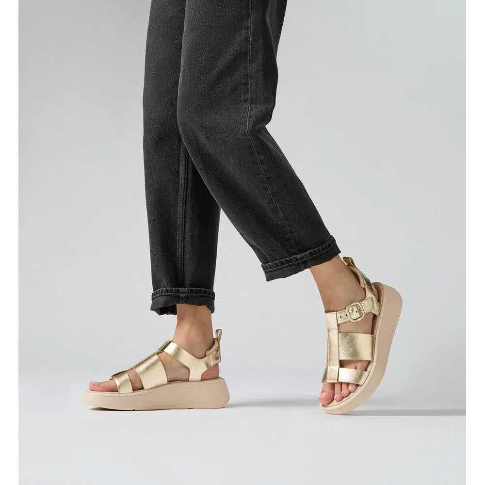FitFlop HV2-675 F-Mode metallic leather platform sandals with buckle, in a platinum color, worn with black rolled jeans.
