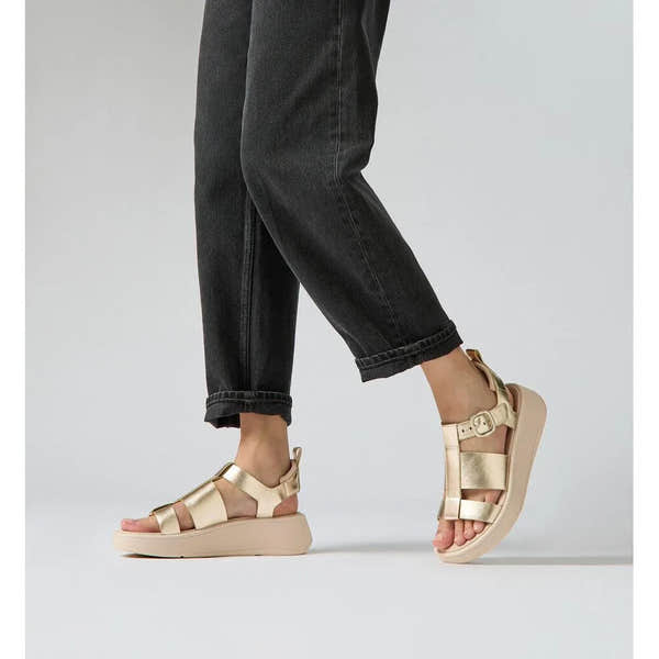 FitFlop HV2-675 F-Mode metallic leather platform sandals with buckle, in a platinum color, worn with black rolled jeans.
