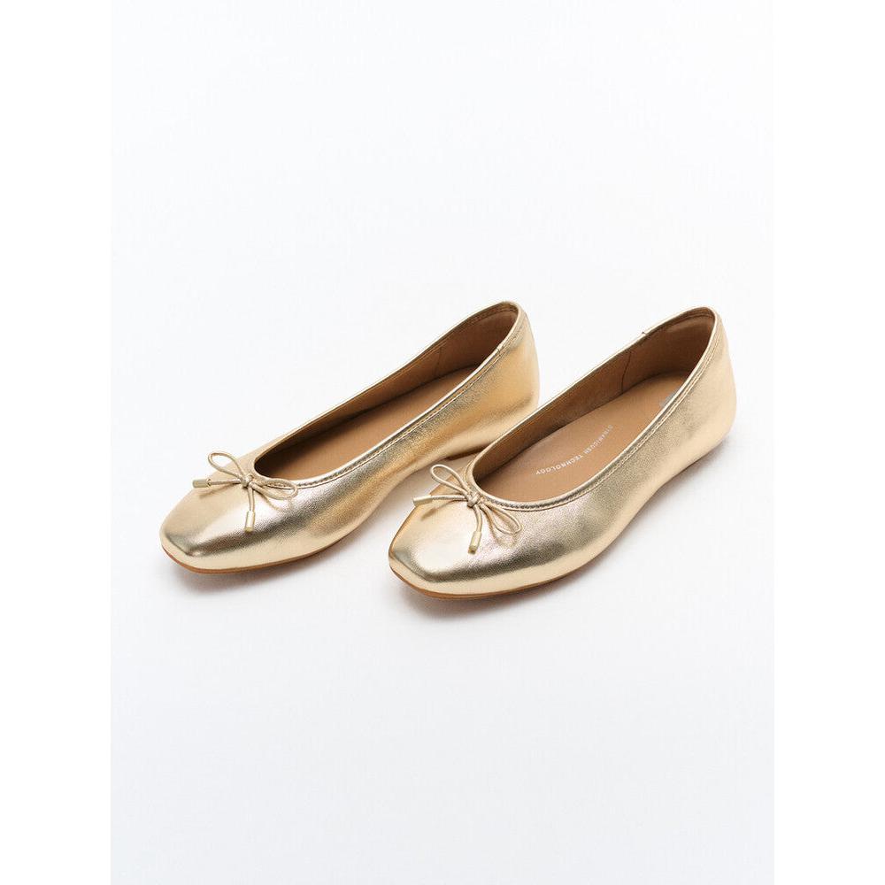Gold metallic leather slip-on ballet flats with a small bow detail for women.