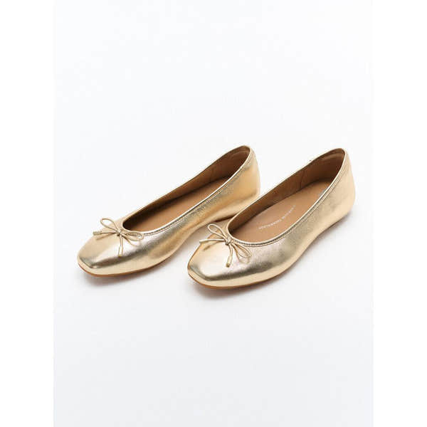Gold metallic leather slip-on ballet flats with a small bow detail for women.