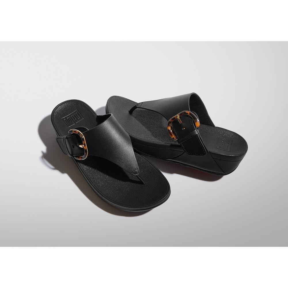 FitFlop Lulu resin black leather slip-on sandals with tortoise buckle detail for women.