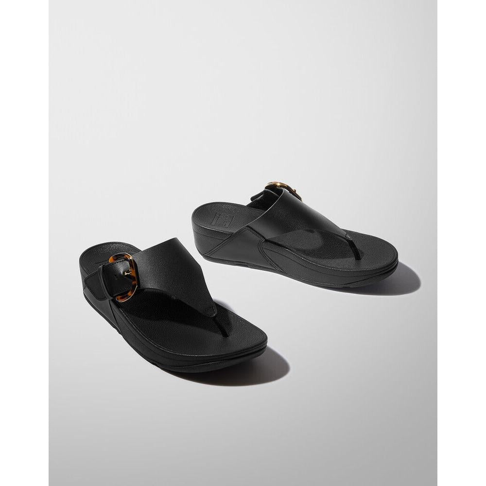 FitFlop Lulu Resin women's black leather slip-on sandals with T-strap design and gold buckle detail.