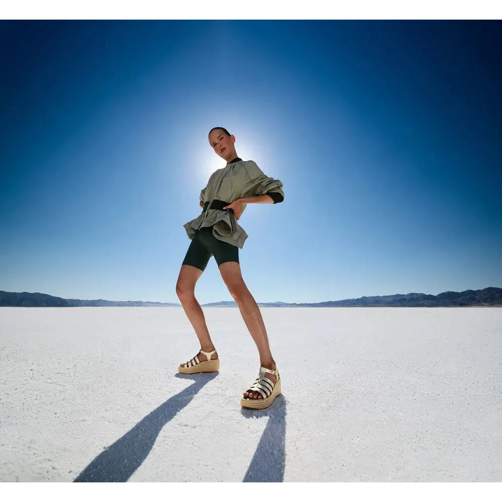 FitFlop JF5-675 platform espadrille women's t-bar sandals in platinum leather, showcased on a model in a desert landscape.