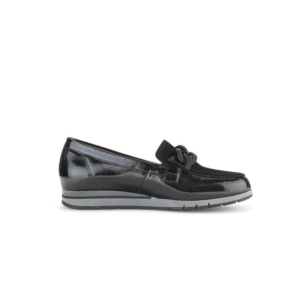 Black patent leather slip-on loafer with bow detail, low wedge heel, and cushioned sole for women.