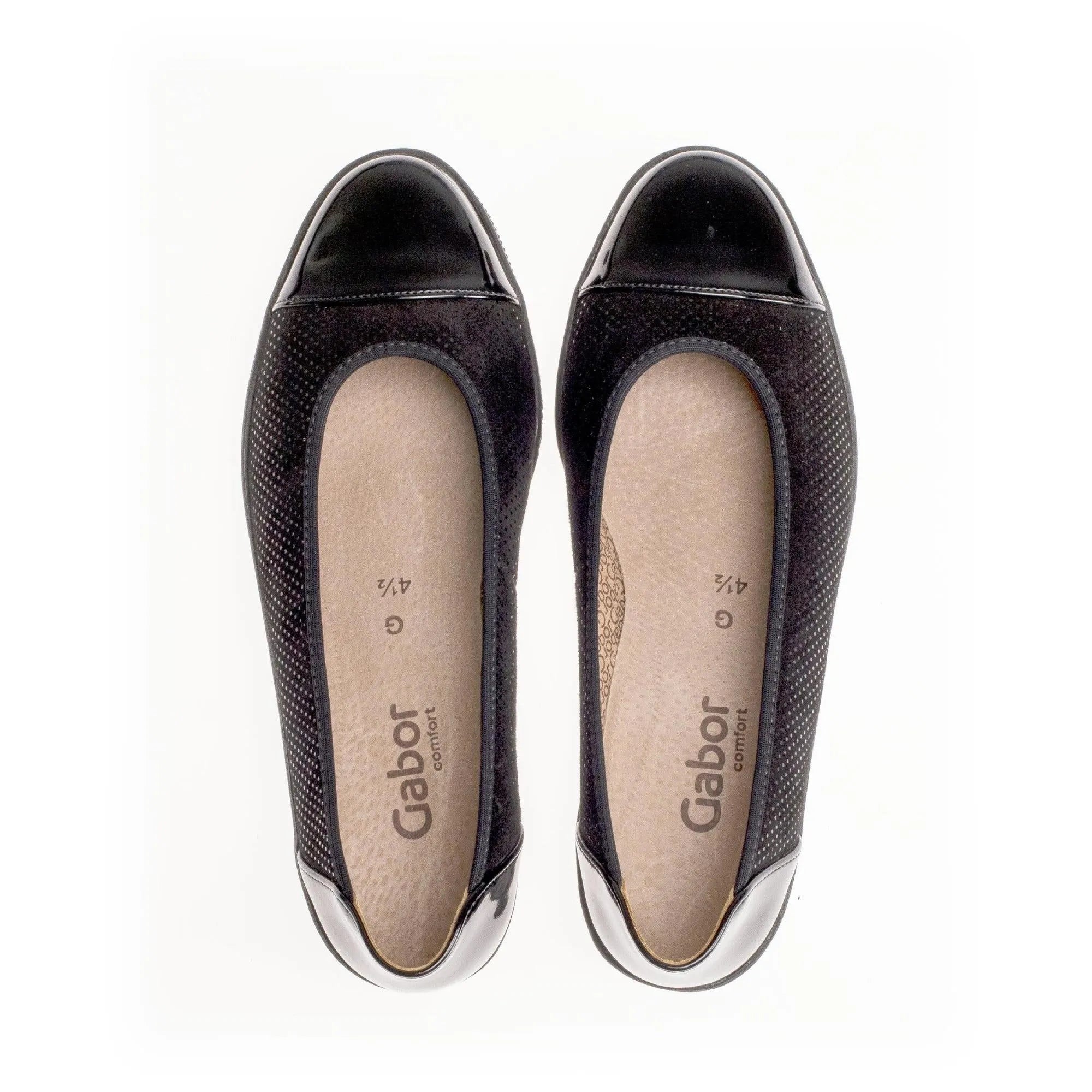 Black patent leather women's slip-on shoes with perforated sides and comfortable beige insoles.