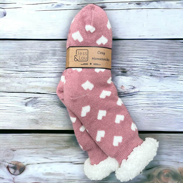Pink cozy lined socks with white heart patterns, perfect for home comfort and warmth.