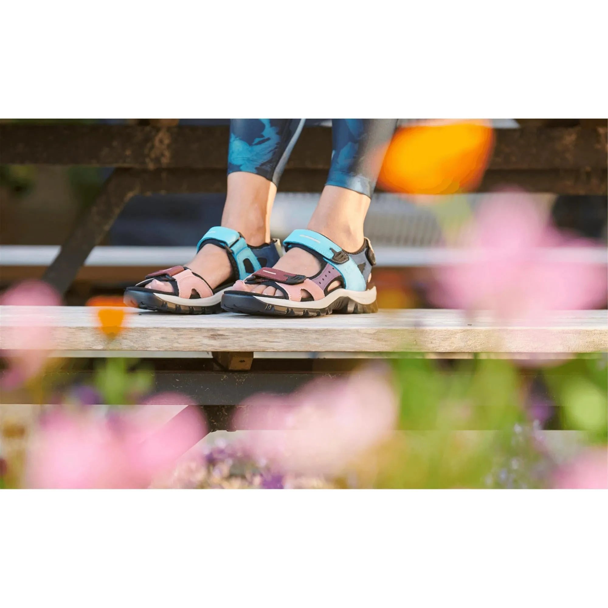 Josef Seibel Bella 10 ladies aqua leather and textile touch fastening sandals on a person standing on a wooden surface, colorful outdoor setting.
