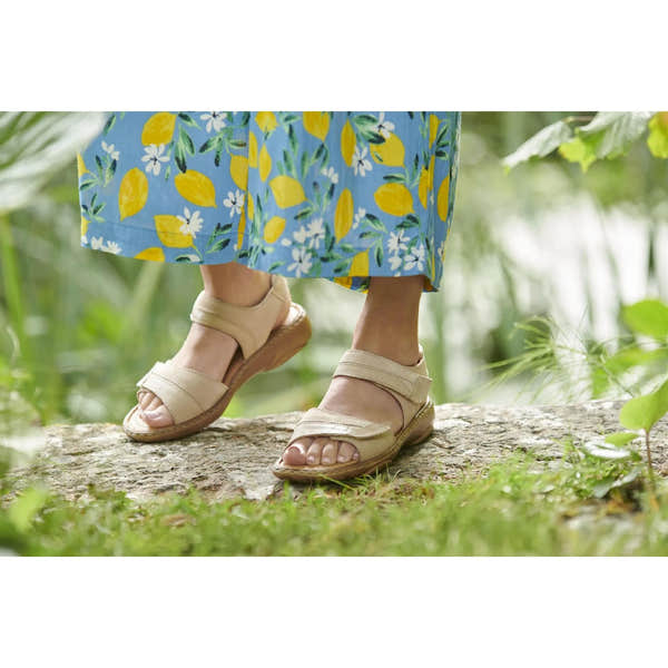 Josef Seibel Debra 19 beige leather touch-fastening sandals worn outdoors with a colorful floral skirt.