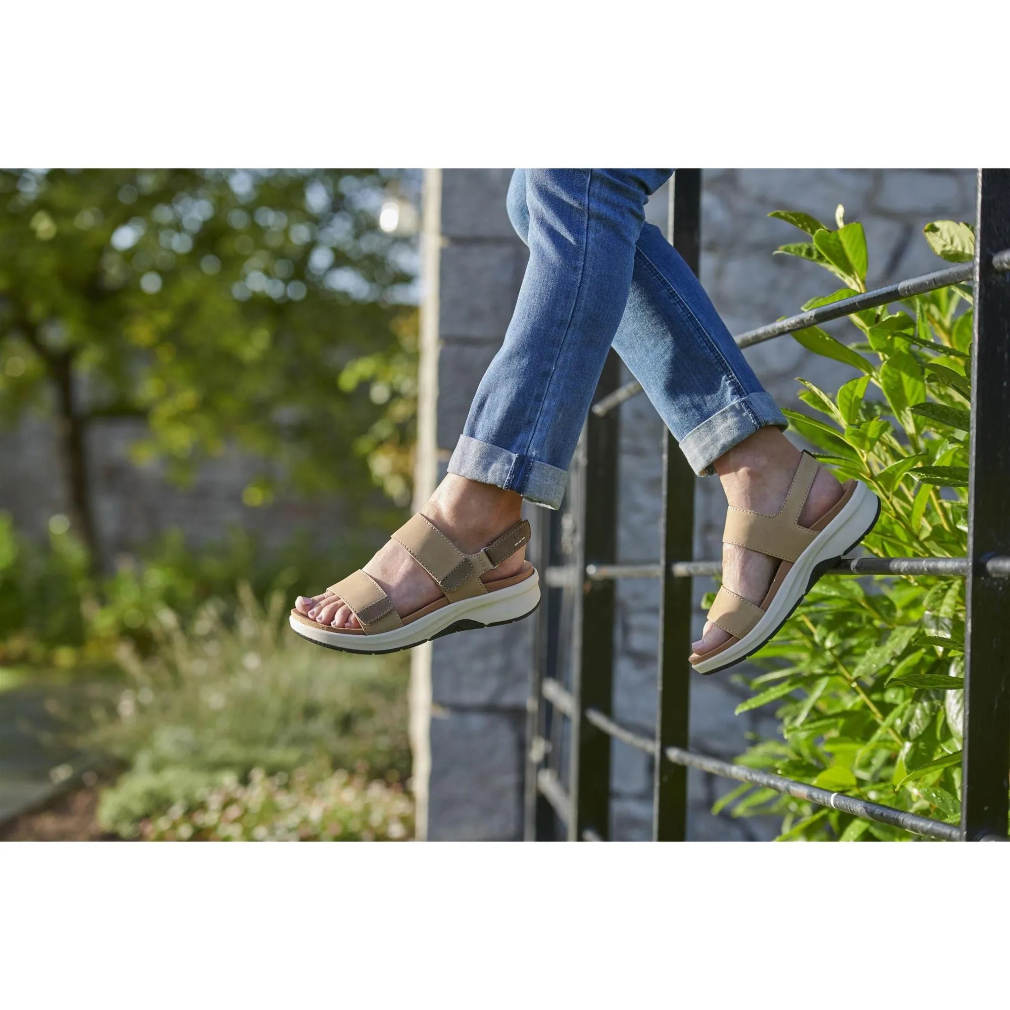 Beige leather sandals with touch fastening, chunky white sole, worn with rolled-up blue jeans outdoors.