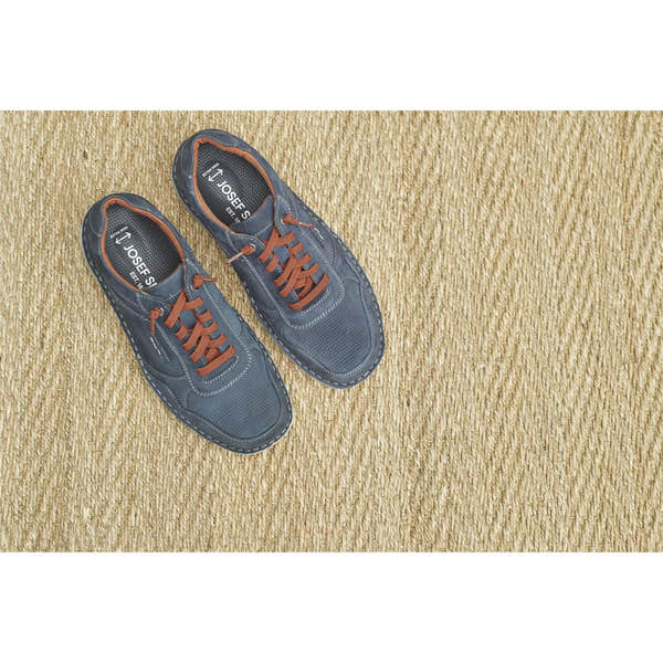 Men's navy blue leather lace-up shoes with orange laces, perforated toe and white stitching, on a woven beige rug.