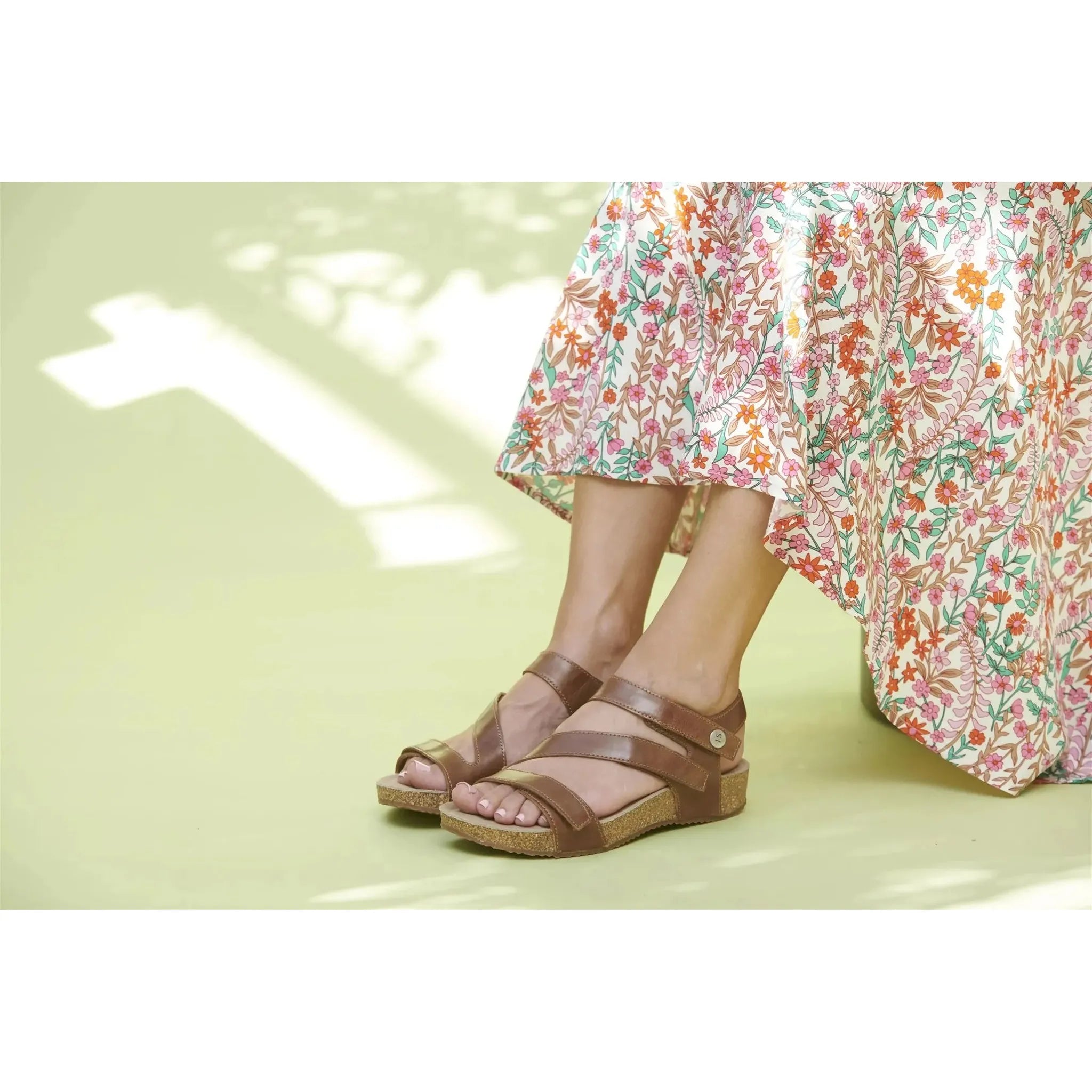 Josef Seibel Tonga 25 Ladies Camel Leather Sandals with adjustable straps and cork sole, worn with a floral dress, on a light green background.