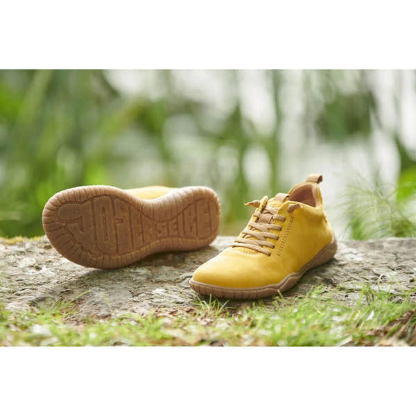 Mustard leather lace-up shoes with a cushioned sole and textured rubber outsole, showcased outdoors on a rock.