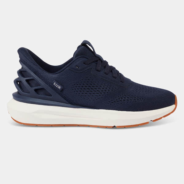 Kizik Athens 2.0 men's navy leather slip-on trainers with arch support, breathable knit upper, cushioned white midsole, and orange rubber outsole.