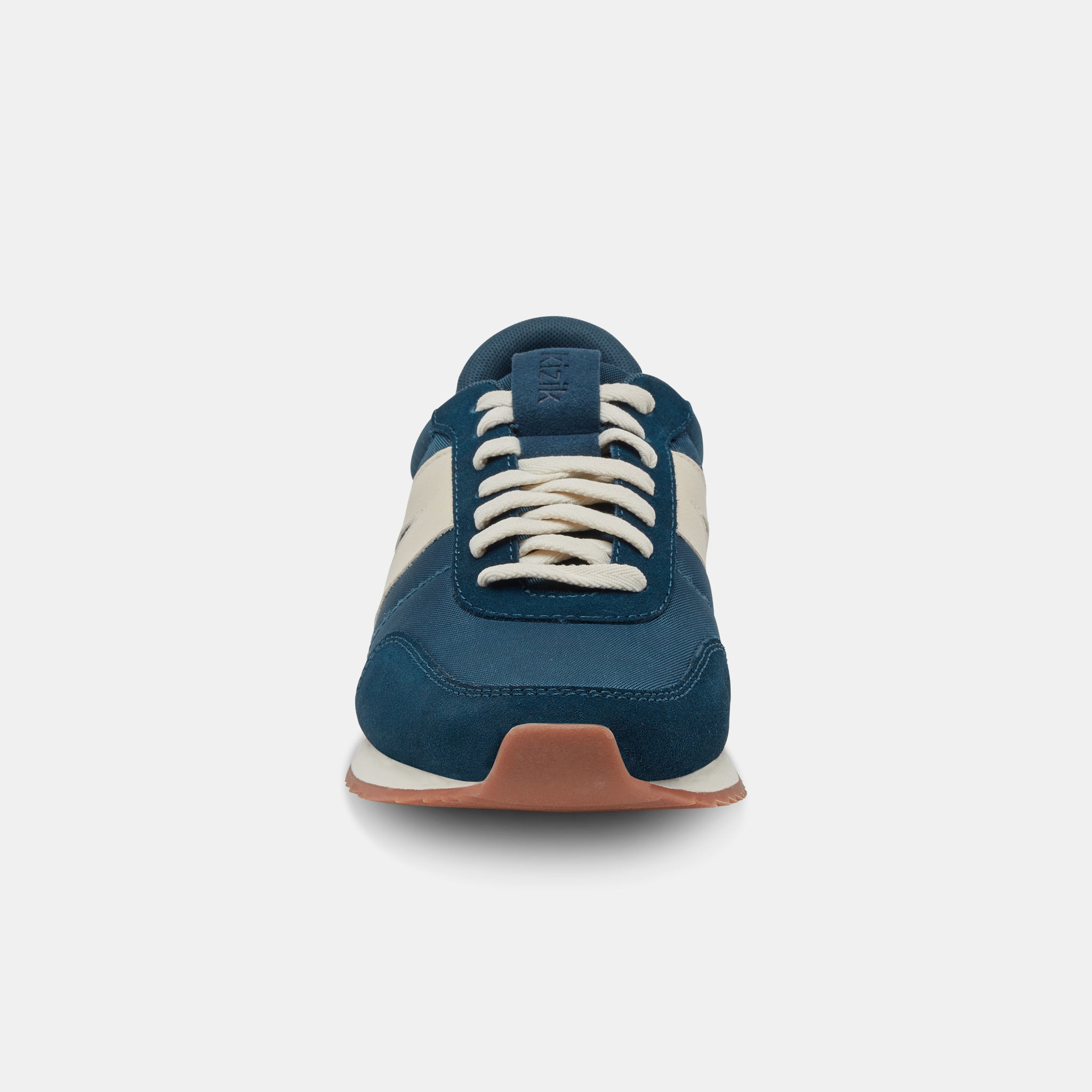 Kizik Milan unisex slip-on trainers in tidepool leather and textile with arch support, white laces, and beige and navy accents.
