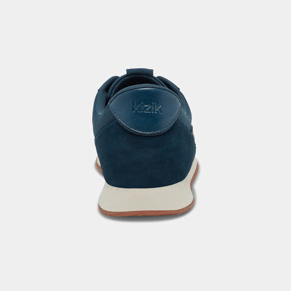 Kizik Milan unisex slip-on trainers with tidepool leather and textile upper, arch support, white sole, black accents.