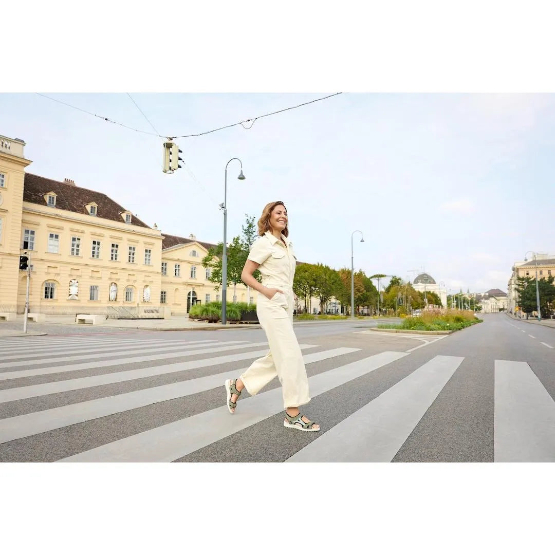 Woman walking on crosswalk wearing Legero Siris multi leather touch fastening sandals in a city street scene.