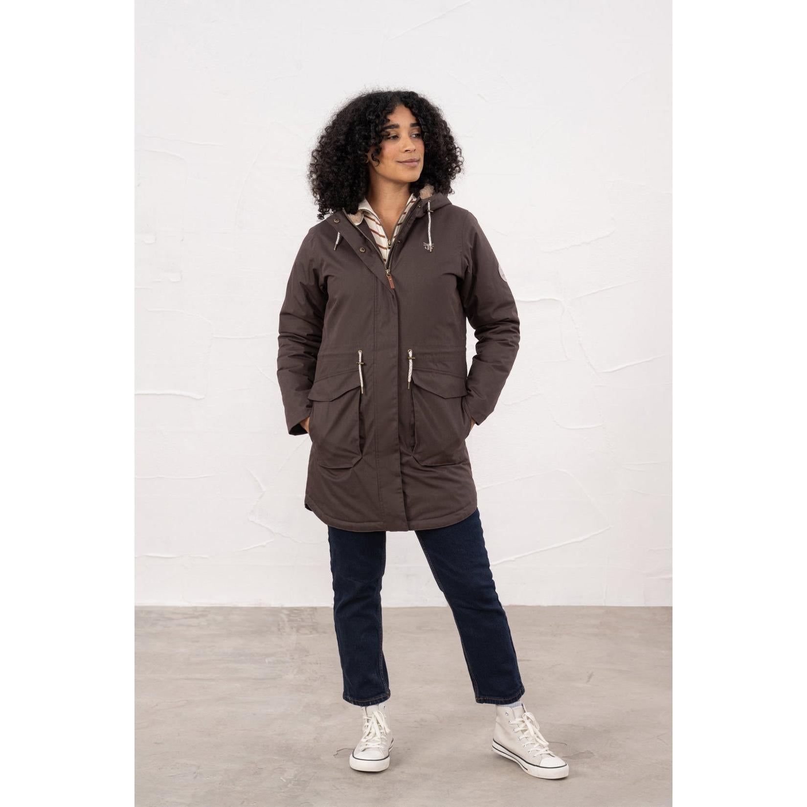 Woman wearing a brown waterproof padded coat with hood, zipper closure, and front pockets, suitable for rainy weather.