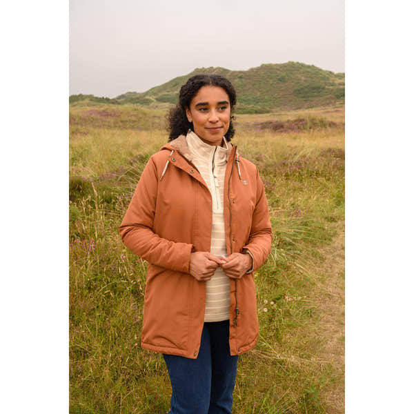 Lighthouse Scarlet Ladies Waterproof Coat in Rust, stylish outdoor jacket with hood, perfect for rainy weather, shown outdoors.