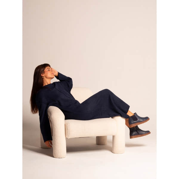 Lunar GLR127 Georgie Ladies Navy Leather Side Zip Ankle Boots with chunky soles, paired with navy knit jumpsuit on model sitting on cream textured armchair.