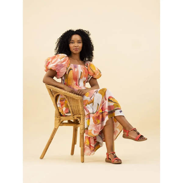 Lunar JLH475 Brava Ladies Orange Elasticated Sandals with ankle straps, worn by a woman in floral dress sitting on wicker chair.