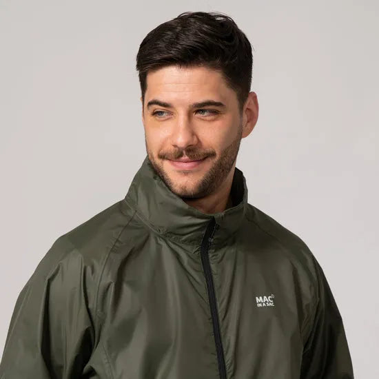 Unisex khaki Mac In A Sac Mias Origin 2 jacket with high collar, front zipper, and logo, worn by a smiling male model.