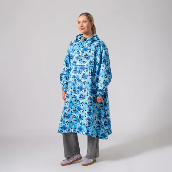 Unisex blue floral festival poncho, waterproof raincoat with hood, oversized fit, worn by woman, casual outdoor rainwear.
