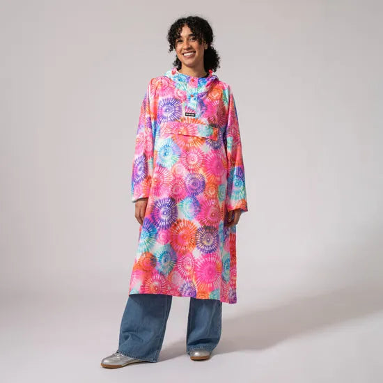 Unisex festival poncho with tie-dye spiral pattern, vibrant colors, long length, worn by a smiling woman.