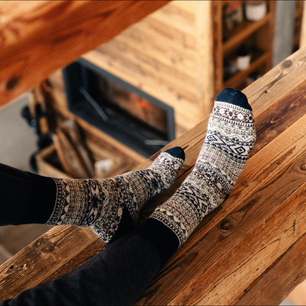 Unisex Nordic Arne Wool Socks in black with traditional Nordic pattern, casual style, worn on a wooden staircase.