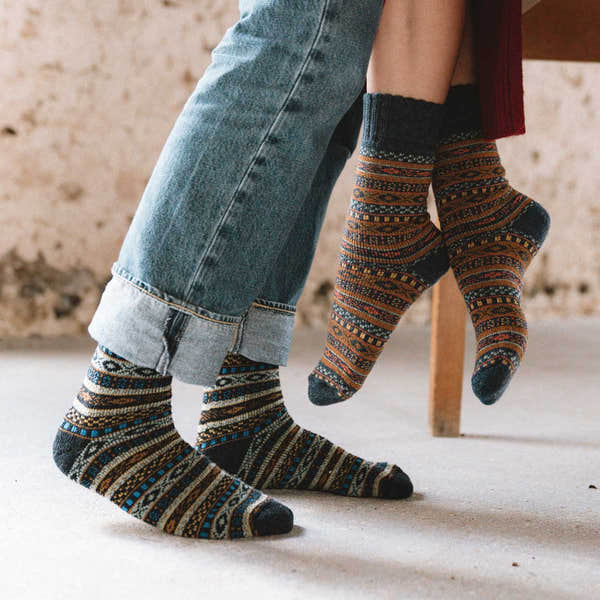 Unisex Arvid Wool Green Nordic Socks, colorful patterned knee-high socks with intricate designs, worn by people sitting.
